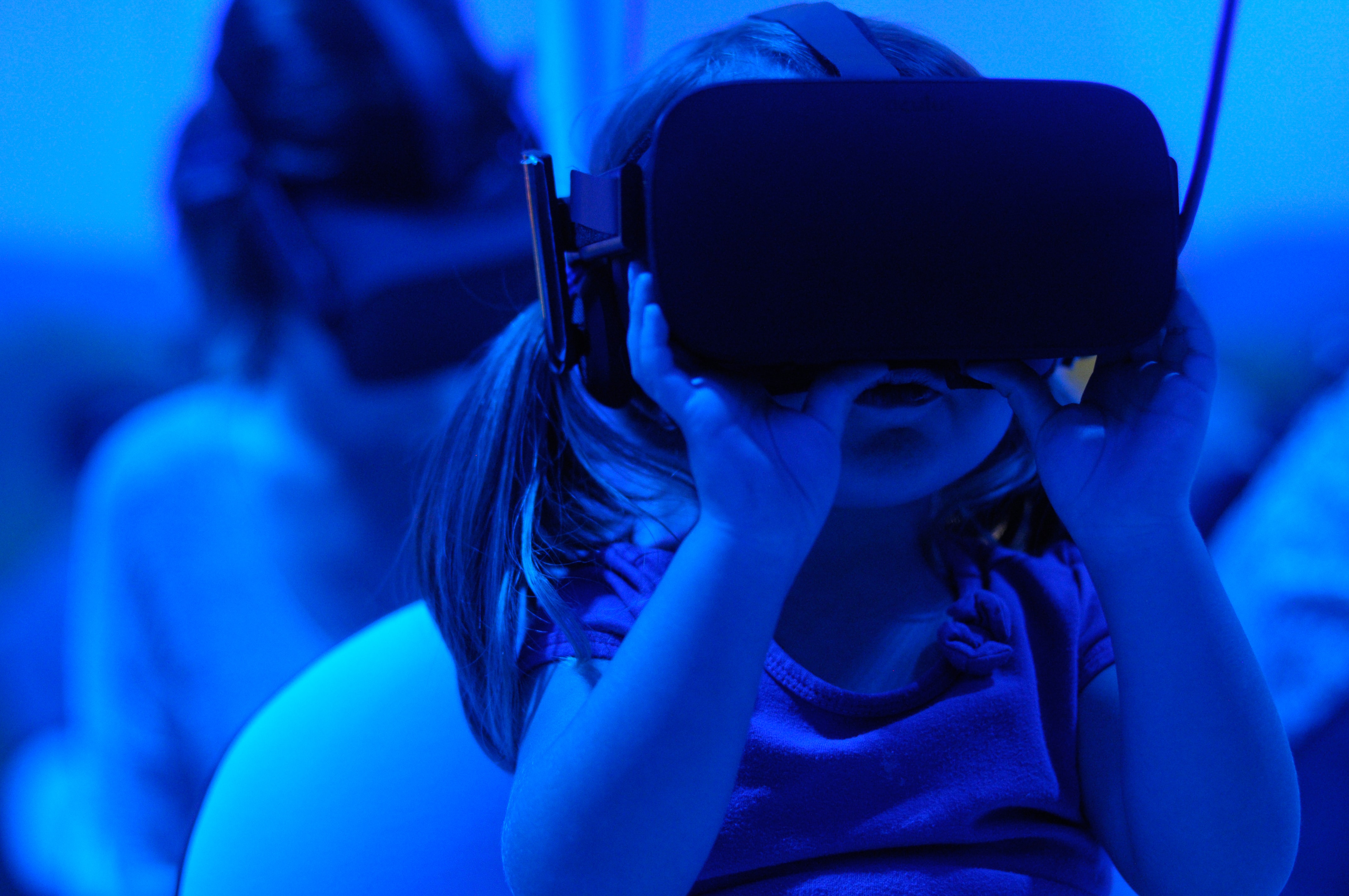 Une petite fille est en train d'essayer les lunettes de vision virtuelle avec le VirtuAll.