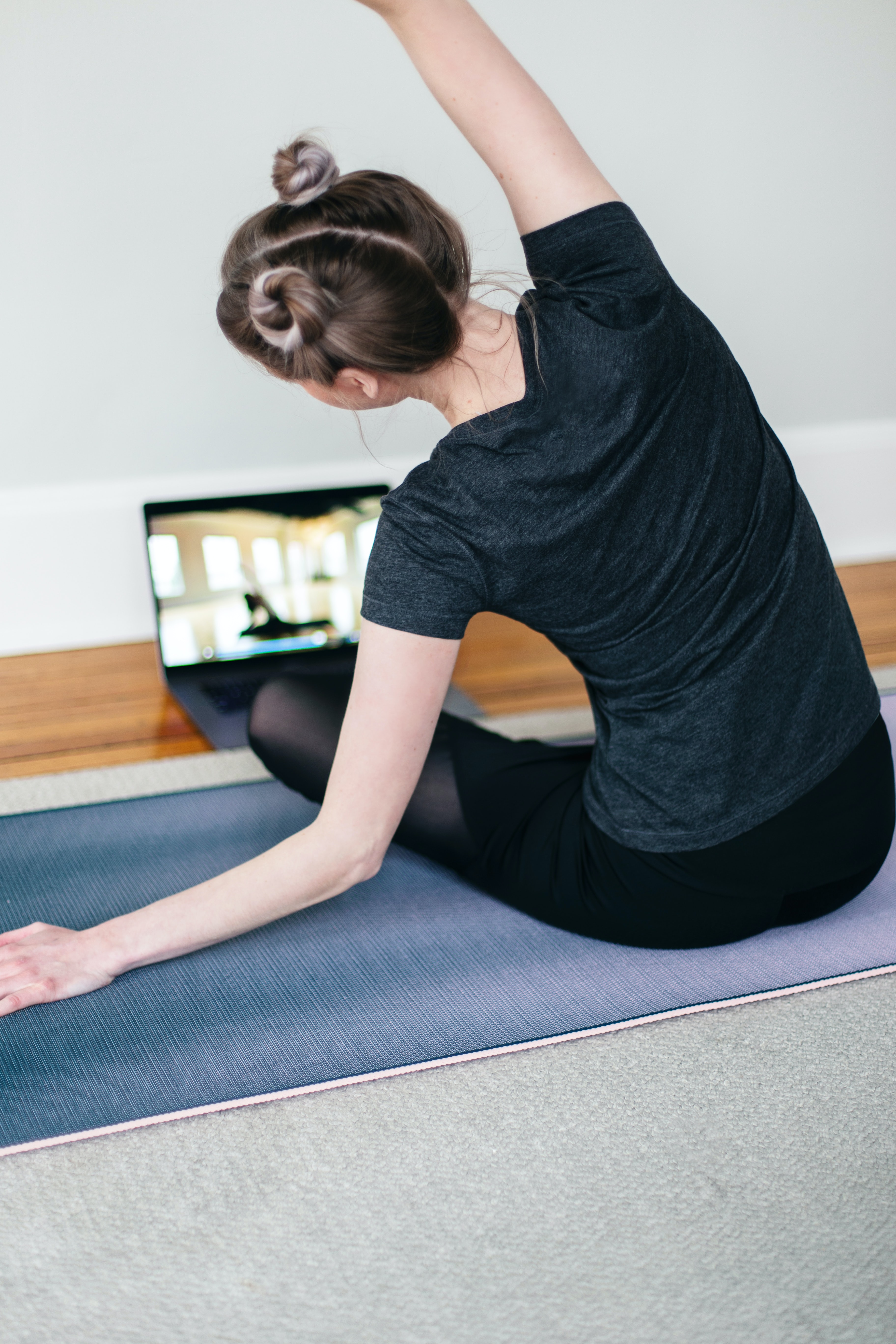 Une femme suit un cours de sport sur son ordinateur portable.