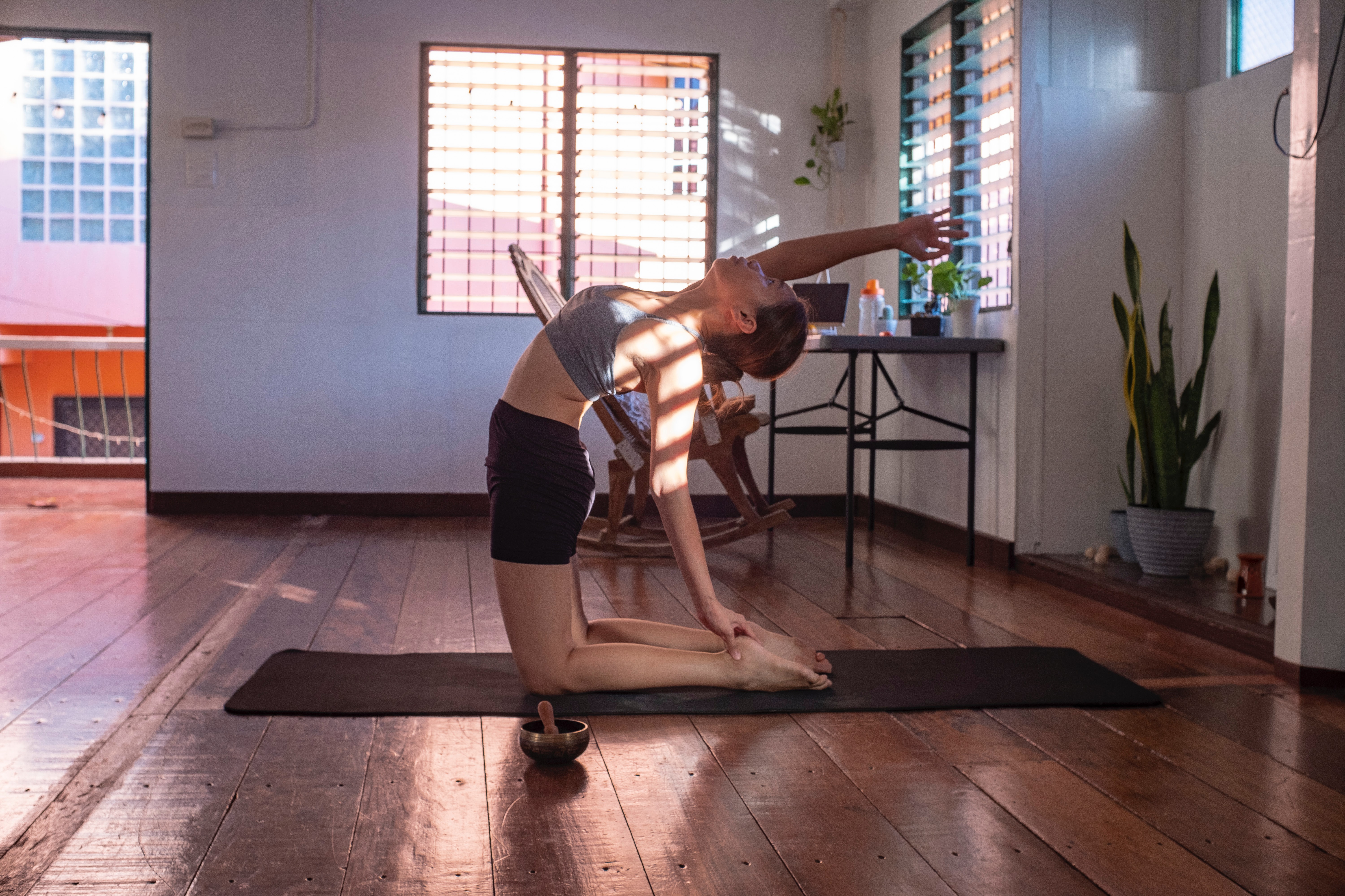 Une dame s'étire en arrière sur un tapis de yoga.