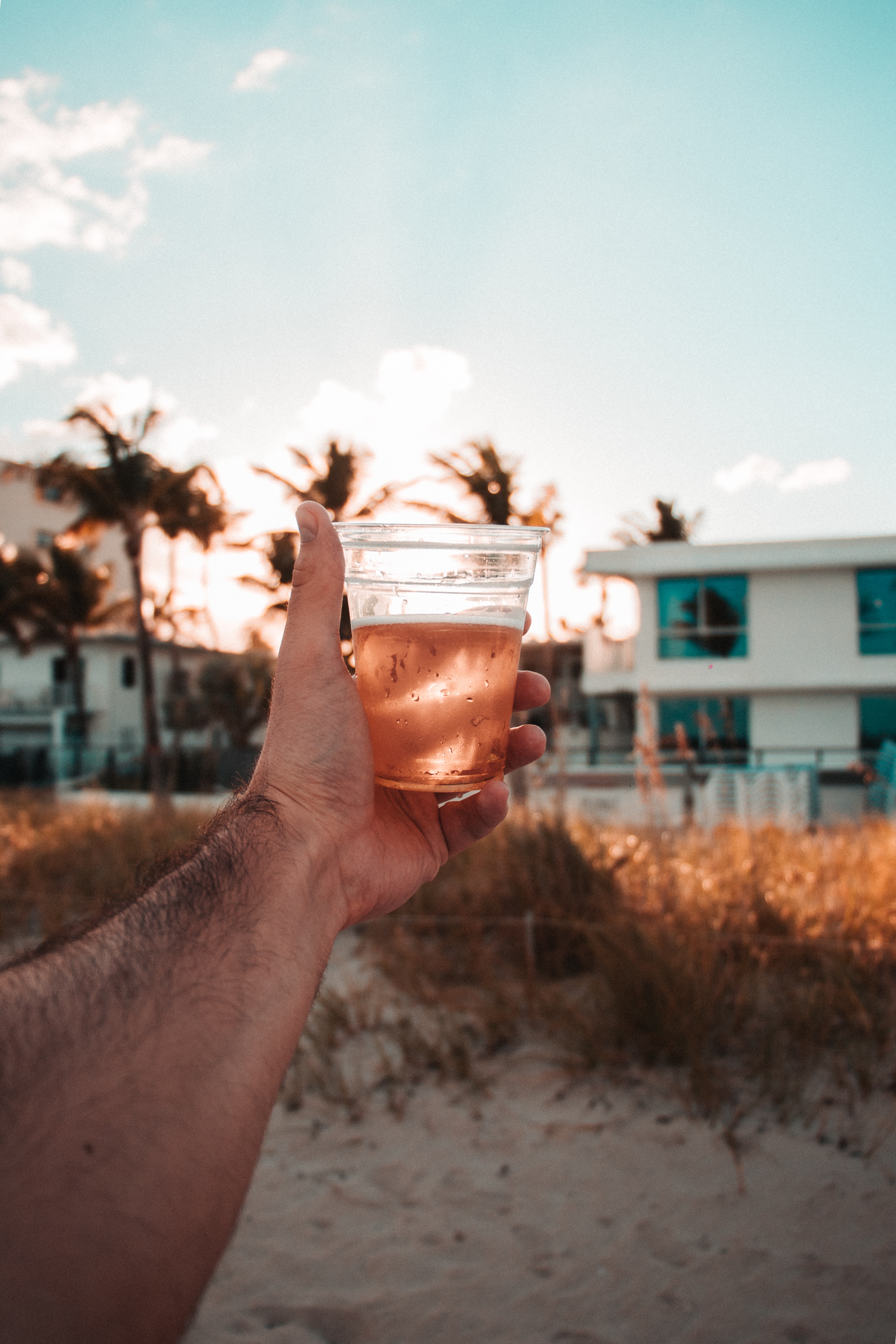 C'est un bras tendu sur une plage, qui tient un verre de bière.
